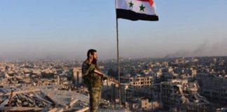 America Bombs Syria, Protects the Terrorists. Where Is The Outrage? Soldier standing on ruined rooftop with Syrian flag