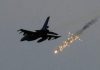 US-led International coalition’s massacres against Syrian people in 2019/The Syria Times Military aircraft releasing flares against a gray sky.