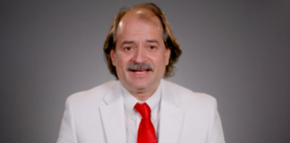 Who is “Winning” and Who is “Losing”/ The “Transnational Corona Crisis” is Fabricated on a Bedrock of Unreliable Evidence. Man in white suit with red tie smiling at camera.