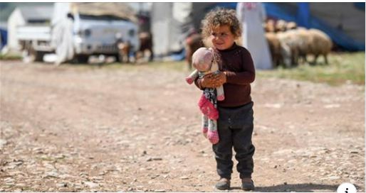 Child holding a doll while standing on a dirt road. Child holding a doll while standing on a dirt road.