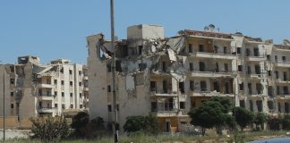 Videos from Syria, 2018 Damaged multi-story building with collapsed sections on a sunny day.