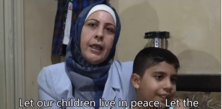 Let Our Children Live In Peace/ report by Vanessa Beeley/ September, 2018 Woman in a headscarf speaks with a young boy beside her.