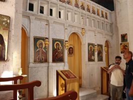 Interior of a church with religious icons and wooden pews.