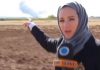 Remembering Serena Shim, By Marwa Osman A woman in a hijab points toward smoke rising in a field.