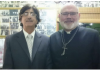Shame on Humanity/ Commentary by Reverend Andrew Ashdown Two men smiling, one in a suit and tie, the other in a black shirt with a cross necklace.