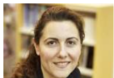 Maria Saadeh, former independent Syrian MP, on the blockade of Syria Portrait of a smiling woman with curly hair in a library setting.