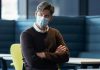 Norwegian Experts Say Deadly Blood Clots Were Caused by the AstraZeneca COVID Vaccine Man wearing a mask and glasses with arms crossed in an office.