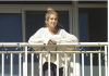 Hero Nurse Fights For Our Rights And Our Lives A woman stands on a balcony, holding a phone and looking away.