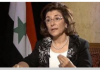 President Assad’s Media Advisor on the Syrian Elections and More/ By RT A woman speaking in front of a Syrian flag.