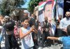 Today I Saw Syrians Dancing and Celebrating Life, and a Return to Peace – but, of Course, the Western Media Won’t Report that/ By Eva Bartlett Young boy and men holding flags and a large portrait in a street gathering.