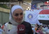 Syrian Women Woman in white hijab speaking at an outdoor event.
