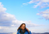 What is happening in Palestine and the region? – Vanessa Beeley interview with Gordon Dimmack Woman in blue coat standing on a scenic hill under a partly cloudy sky.