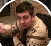 2012 Defense Intelligence Agency document: West will facilitate rise of Islamic State “in order to isolate the Syrian regime”/ By Brad Hoff Man in a patterned sweater holding a drink, sitting outdoors.