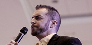 Recent Rise of ISIL in Afghanistan Explained/ By Adam Kokesh Man speaking into a microphone wearing a suit.
