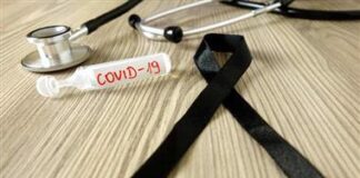 The Vaccine Death Report: Evidence of Millions of Deaths and Serious Adverse Events Resulting from the Experimental COVID-19 Injections/ By David John Sorensen and Dr. Vladimir Zelenko A COVID-19 test tube and a black mourning ribbon on a wooden surface.