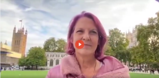 Anna De Buisseret Legal Cases Against Those Committing Crimes Against Humanity With the Jabs Woman with pink hair speaking outdoors near a white building.