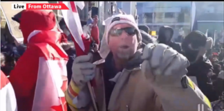 Live Trucker Convoy from Ottawa Man in protective gear holding a tool at a protest or rally.