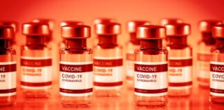 Myocarditis Tops List of COVID Vaccine Injuries Among 12- to 17-Year-Olds, VAERS Data Show Close-up of COVID-19 vaccine vials with a red-orange background.