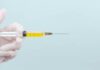 Alberta Canada Inadvertently Published (and Quickly Deleted) Health Data Exposing that More Than Half of Vaccinated Deaths Have Been Counted as Unvaccinated/ By Julian Conradson A syringe filled with yellow liquid against a light blue background.