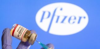 Pfizer/FDA Corruption, Lethal Batches, and Autopsies Reveal COVID-19 Jab Genocide A syringe drawing vaccine from a vial with Pfizer logo in the background.