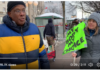 Canada is in Peril/ Commentary by Ormond Chalmers Man in blue and yellow jacket at outdoor protest holding a bright green sign.