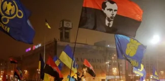 History of Ukraine’s Nazi Connection/ By Brett Redmayne-Titley Crowd with Ukrainian and nationalist flags at night rally.