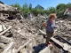 Ukrainian Army Shelling of Donbass: A Day in Hell Without End/ By Christelle Néant A woman stands amid rubble and debris in a devastated area.