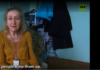 Refugee Describes Azov Atrocities A woman sitting in a room with clothes and a subtitle visible.