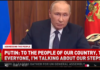 Partial Military Mobilization in Russia to Defend Russia Against NATO, Nazis A man in a suit speaking at a wooden panel desk.