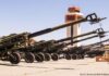 The Military-Industrial Complex Offensive/ By Manlio Dinucci A row of artillery cannons lined up outside a military building.