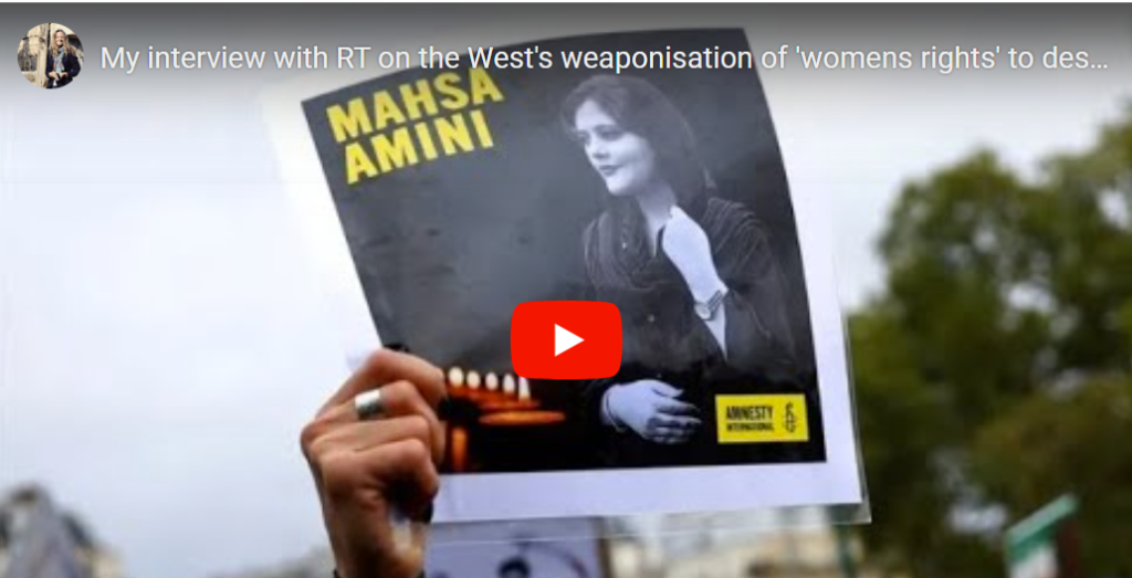 Person holds a poster of Mahsa Amini with a YouTube play button overlay.