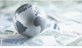 A gray globe resting on scattered US dollar bills.