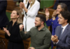 Canada’s Morally Bankrupt, Nazi-Supporting Political Class A man in a green shirt claps with others in a formal setting.