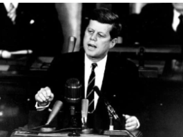 John F. Kennedy delivering a speech behind microphones.