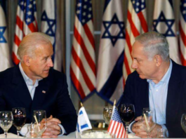 Two politicians engaged in discussion with US and Israeli flags behind.