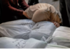 Palestine: Not All of the Genocide Is Happening Before Our Eyes. Paul Larudee Person in distress lying on a bed with supportive hands nearby.