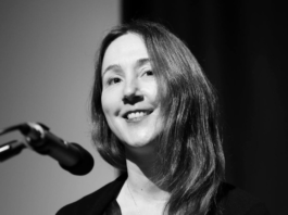Woman smiling near a microphone in black and white.