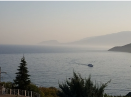 Calm lake with distant mountains and a boat moving across the water.