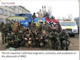 Group of armed men dressed in Nazi and other military-style uniforms posing with flags.