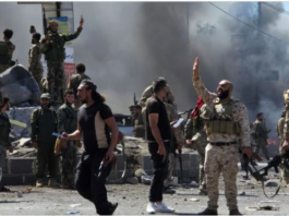 Armed men in tactical gear in a smoke-filled urban area.