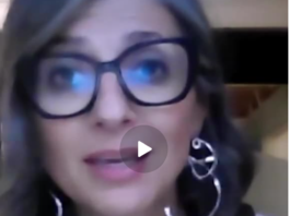 A woman with glasses speaking in a video call.