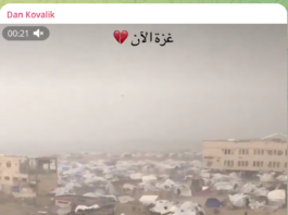 Flooded area with tents and buildings under a cloudy sky.