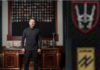 The Silence of the West Speaks Volumes/ Links via Eva Bartlett Man in black standing before military patches