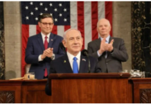 The War Against Iran: 30 Years in the Making/By Professor Piers Robinson Speaker at podium with American flag