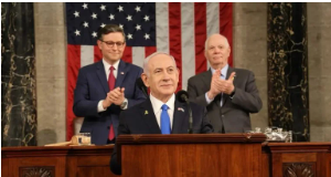 The War Against Iran: 30 Years in the Making/By Professor Piers Robinson Speaker at podium with American flag