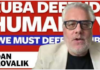 We must defend Cuba: Dan Kovalik Speaker with glasses before "Cuba Defends Humanity" banner