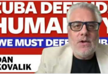 We must defend Cuba: Dan Kovalik Speaker with glasses before "Cuba Defends Humanity" banner