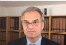 Free Reiner Fuellmich – The Documentary Man in suit and glasses, bookshelf background